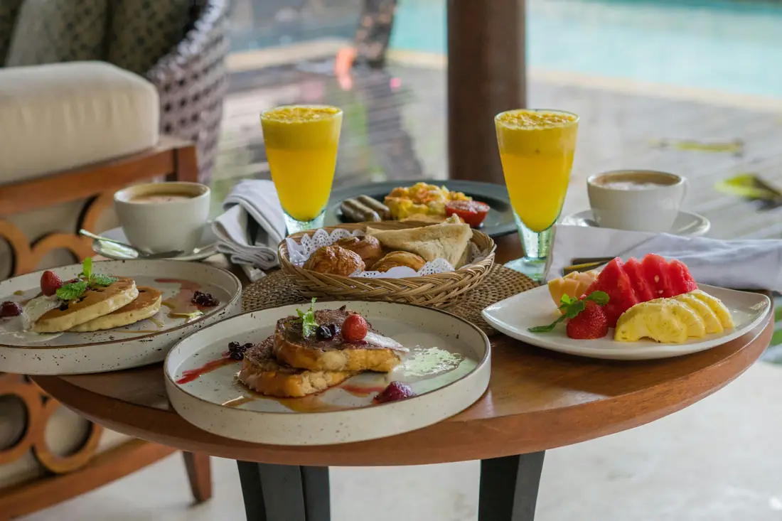 A breakfast table with fruit, pastries, juice, and coffee.