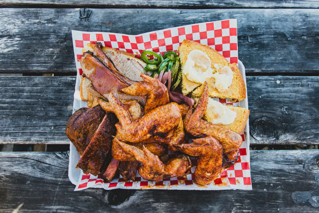 Mixed grill platter with assorted meats, toast, peppers, and sauces.