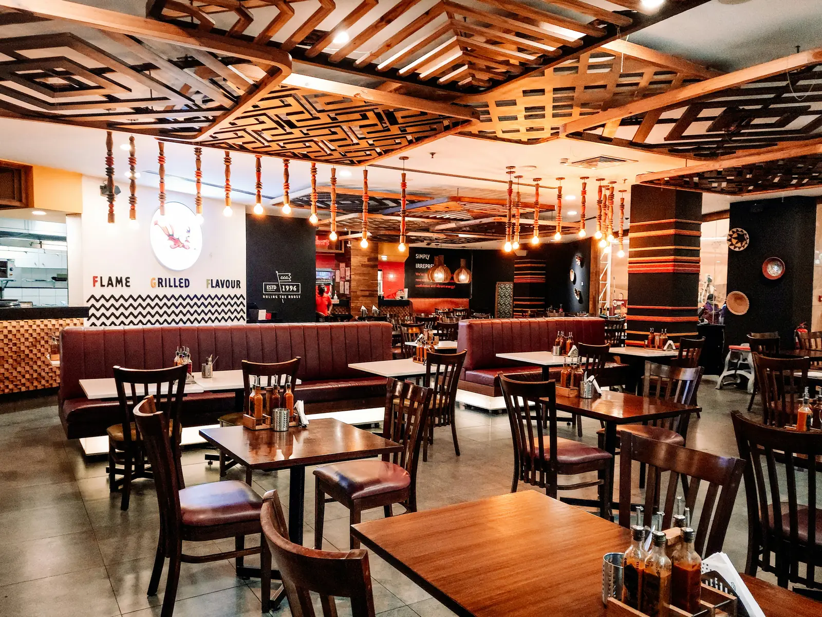 Warm restaurant dining room with tables, booths, and hanging lights.